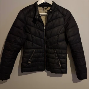 Svart pufferjacka från Njord, S - Svart pufferjacka från Njord med snygg quiltad design och raka linjer. Jackan har två snedställda fickor med dragkedja och hel dragkedja framtill. Perfekt för kyliga dagar och har en stilren look som funkar till det mesta.