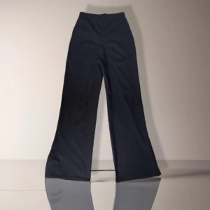 Svarta vida byxor från Boohoo - Svarta byxor från Boohoo med vida ben. Byxorna har slits nertill på benen och är gjorda i ett mjukt, stretchigt polyestertyg. 