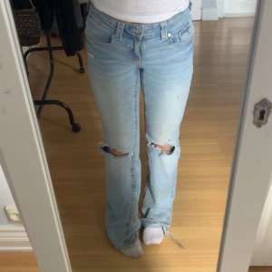 Ljusblå bootcut jeans Gina Tricot  - Ljusblå jeans från Gina Tricot i storlek 164. Modellen är bootcut, slitningar vid knäna och råa kanter nertill. Klassisk femficksdesign och låg midja. Perfekta för dig som gillar en avslappnad och trendig look. Hål i rumpan men kan man sy är det lätt att laga. Har gått sönder de lite där nere så men det kan man med laga om man är duktig på det 