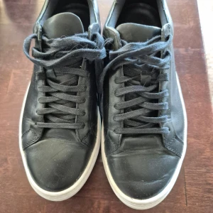 Svarta sneakers från Vagabond - Svarta sneakers från Vagabond i klassisk design. Skorna har svarta snören, vit platt sula och rund tå. Perfekta för dig som gillar en stilren och enkel look. Passar till det mesta och är lätta att matcha med olika outfits. Är använda men i gott skick, se bilder för skavanker.