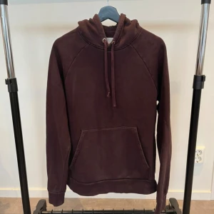 A days march hoodie Vinröd - Säljer en vinröd hoodie med huva och snörning. Tröjan har en stor magficka framtill och långa ärmar. Perfekt för dig som gillar en enkel och stilren look. Materialet känns mjukt och skönt mot huden.