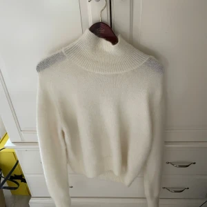 Vit mohair tröja från H&M Edition - Supermjuk och fluffig vit mohair tröja från H&M Edition. Tröjan är stickad med hög krage och har långa ärmar samt ribbade muddar. Perfekt för kyliga dagar och ger en clean och stilren look. Den är aldrig använd!