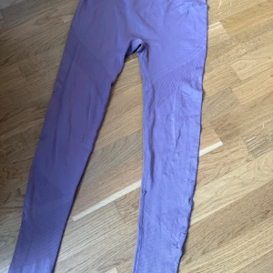Lila seamless leggings i stretch - Säljer ett par lila seamless leggings i mjukt och stretchigt material. De har ribbade detaljer vid benslut och runt knäna för extra stil och komfort. Perfekta för träning eller chill dagar. Materialet är en blandning av polyamid, polyester och elastan.