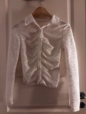 Vit strukturerad skjorta med knappar - En vit skjorta med knappar på, det är mönster på den! Inte använd alls mycket PS! Om du köper innan 17 så postar jag samma dag🥰