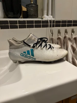 Vita Adidas fotbollsskor med blå logga - Ett par Adidas X i storlek 44. Har lite småskador men är fortfarande i ett väldigt bra skick. Är en äldre och unik modell och väldigt svåra att få tag i. 