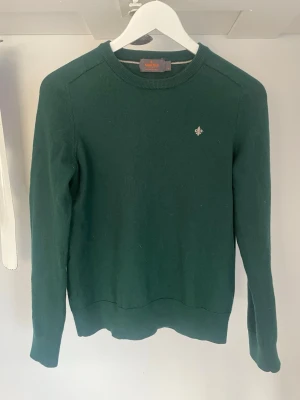 Mörkgrön merinoullströja Morris M - Säljer en mörkgrön tröja från Morris i 100% merinoull. Klassisk rund halsringning och Morris-logga broderad på bröstet. Långärmad modell med ribbade muddar vid ärmslut och nederkant. Perfekt för dig som gillar stilrena plagg. Storleken är från början M men har krympt till xs! Den är inget konstig i storleken utan precis som XS. Skriv om ni har några funderingar eller vill diskutera priset!