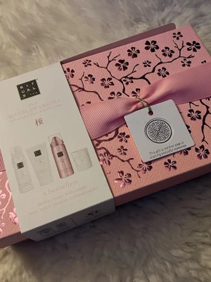 The Ritual of Sakura presentbox (Ny!) - Lyxig presentbox från Rituals i serien The Ritual of Sakura. Innehåller fyra bästsäljare: shower foam, body cream, body lotion mousse och doftljus. Snygg rosa ask med blommönster och rosett, perfekt som gåva.