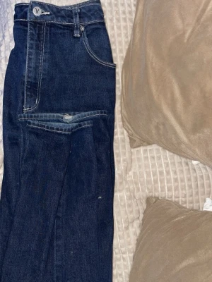 Mörkblå jeans från Abrand - Snygga mörkblå jeans från Abrand med raka ben och kontrastsömmar. Klassisk femficksmodell och hög midja. Perfekta för dig som gillar en tidlös och clean look. Jeansen är i denim och har en diskret logga på linningen.