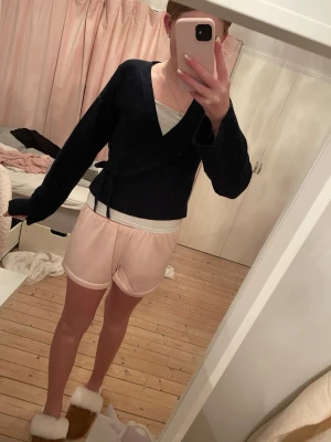 Marinblå omlottkofta med knytband - Mysig marinblå omlottkofta med långa ärmar och knytband i midjan. Koftan har en djup v-ringning och är ribbstickad nedtill. Perfekt att slänga på sig över ett linne eller t-shirt för en chill look. I storlek 158/164 men sitter som XS