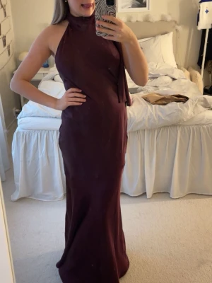 Balklänning - Säljer denna så fina burgundy färgade balklänning som är halterneck och öppen i ryggen! Helt oanvänd med prislapp kvar