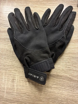 Svarta Ridhandskar  - Svarta handskar från Ariat med justerbart kardborreband vid handleden. Använda fåtal gånger och är i nyttskick, ca 7 i storlek 