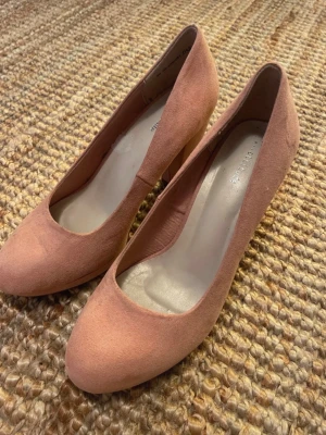 Rosa mocka klackskor  - Snygga rosa pumps från attitude i mjuk mocka. Skorna har rund tå och klassisk klack som ger en elegant siluett. Perfekta för dig som vill ha en stilren och feminin look.