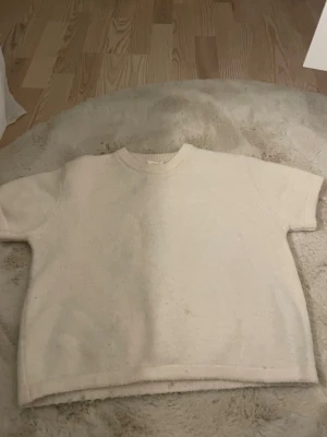 Vit stickad tröja Gina Tricot - Kortärmad, vit stickad tröja från Gina Tricot. Tröjan har en rak passform och ribbstickad halsringning. Perfekt att styla med jeans eller kjol för en enkel och clean look.