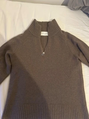 Brun stickad halvzip från A DAY’S MARCH - Mysig brun stickad tröja från A DAY’S MARCH med hög krage och halvzip-dragkedja. Tröjan har långa ärmar och bred ribbstickad kant nedtill och vid ärmsluten. Perfekt för lager på lager och chill höststil.