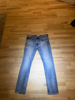 Ljusblå Calvin Klein straight jeans - Säljer ett par ljusblå jeans från Calvin Klein med slitna detaljer och klassisk femficksmodell. Jeansen har rak passform och normal midja. Materialet är bomull med en skön jeanskänsla. Perfekta för en avslappnad och trendig look.