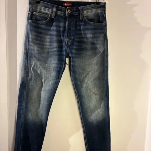 Jack & Jones – Tapered/Erik jeans (stl 32/32) - Säljer ett par blå jeans från Jack & Jones i modellen Tapered/Erik. Jeansen har en avsmalnande passform, klassisk femficksdesign och en snygg tvätt med naturliga slitningar. Storlek 32/32. De är använda men i bra skick utan hål eller skador. Nypris 699 kr.