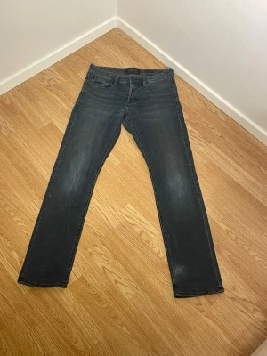 Blå jeans från Superdry - Snygga blå jeans från Superdry med klassisk femficksdesign och detaljerade sömmar. Jeansen har en rak passform och subtila slitningar för en avslappnad look. Tillverkade i mjuk bomullsdenim med Superdry-logga på fickan. W30/L32