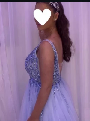 Ljusblå långklänning med paljetter - Elegant ljusblå långklänning med smala axelband och öppen rygg. Klänningen har ett glittrigt paljettliv och ett voluminöst, svepande kjolparti i tyll. Perfekt för bal eller festliga tillfällen. Pris går att diskutera. Bra för korta och långa tjejer, även me små och stora byst, passar även för storlek 38