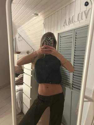 Mörkgrå croppad stickad topp - Snygg mörkgrå croppad stickad topp med ärmlös design. Perfekt att styla med höga byxor eller kjol för en trendig look. Mjuk och fluffig känsla, passar dig som gillar en avslappnad men cool stil. Står ingen storlek men passar mig som annars har xs/s