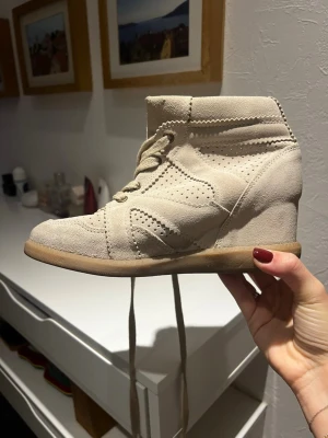 Beige mocka boots med kilklack - Snygga beige boots i mocka med kilklack och snörning från Pavement i storlek 37. Skorna har perforerade detaljer och en platt sula framtill. Perfekta för dig som vill ha både stil och komfort i vardagen. Har ett par likadana i svart men just denna färgen kommer inte så mycket till användning i min garderob. Nypris: 1699kr. Skriv vid fler frågor. Kolla gärna in alla bilder🖤🖤