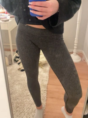Mörkgrå ribbade leggings - Snygga mörkgrå leggings med ribbad struktur och hög midja. Perfekta för en chill och sportig look. Stretchigt material som sitter tight och bekvämt. Passar till både oversized tröjor och crop tops.
