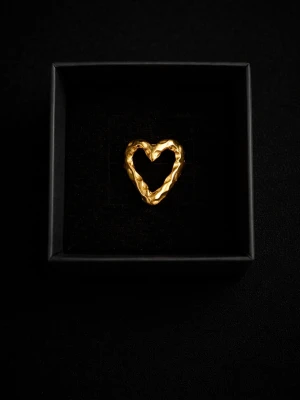 Guldfärgad hjärtformad ring - Trendig ring i guldfärg med unik, skulpterad hjärtform. Perfekt accessoar för dig som gillar statement-smycken och vill sticka ut med en cool och modern look. Ringen har en öppen design och är tillverkad i metall.