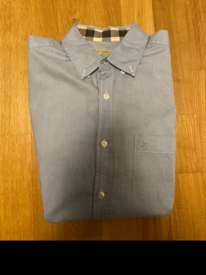 Blå Burberry skjorta ljusblå M - Säljer en äkta burberry skjorta i storlek M. Den är väldigt fin och kostar ca 4000 kr ny, mitt pris är endast 749! Hör av dig vid frågor😁