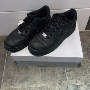 Svarta Nike Air Force 1 - Säljer ett par klassiska svarta Nike Air Force 1 sneakers. Skorna har en stilren design med snörning och en robust sula. Perfekta för en casual look. (knappt använda) st 38 är villig att gå ner i pris om det önskas