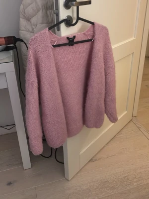 Ljusrosa eftertraktad slutsåld lindex kofta - Mysig ljuslila stickad kofta från Vero Moda med öppen front och lång ärm. Koftan har en avslappnad passform och är gjord i ett fluffigt, mjukt material som känns skönt mot huden. Perfekt att slänga över en topp för en chill look.