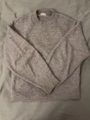 Ljusgrå stickad tröja i ullmix - Mysig ljusgrå stickad tröja med rund halsringning och ribbade muddar vid ärmslut och nederkant. Tröjan har en klassisk, rak passform och är helt perfekt lite kyligare dagar❤️