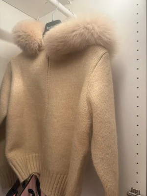 Beige kofta med pälskrage - Mysig beige kofta/jacka med dragkedja och stor fluffig pälskrage. Fick de i julklapp och har tyvärr inte använt den 1 ända gång därav säljer jag den. Den är alltså helt helt ny! Skriv om ni vill ha fler bilder osv!! Den är köpt från märket Alessa för 2200 men säljer för 2000