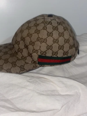 Gucci keps med GG-mönster(ÄKTA) - Snygg keps från Gucci i beige canvas med klassiskt GG-monogram över hela kepsen. På sidan finns den ikoniska gröna och röda randen. Perfekt accessoar för att lyfta din streetwear-look. Priset är hög eftersom den har inga skador och är använd vid 7-8gånger  😁