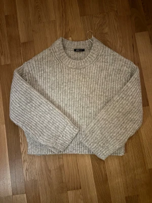 Beige stickad tröja från Gina Tricot - Mysig beige stickad tröja från Gina Tricot med grovstickat mönster, rund halsringning och ribbade muddar vid ärmslut och nederkant. Perfekt för lager-på-lager och enkel att matcha med jeans eller kjol. Slits på sidorna! Super skön ❤️
