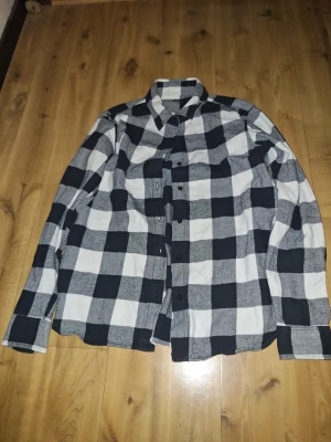 Rutig skjorta från Uniqlo - Klassisk svart och vit rutig skjorta från Uniqlo i storlek XS. Skjortan har långa ärmar, knappar framtill och en mjuk bomullskänsla. Perfekt för en avslappnad och stilren look.