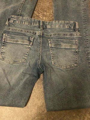 Blåa lågmidjade jeans - Snygga blå jeans med lätt slitningseffekt och klassisk femficksdesign. Lågmidjade.