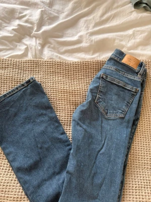 Blå raka jeans från Perfect Jeans - Säljer ett par klassiska blå jeans från Perfect Jeans med raka ben och femficksmodell. Jeansen har normalhög midja, silverfärgad knapp och detaljer i koppar. Perfekta till vardagslooken och passar till det mesta.