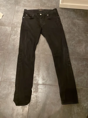 Svarta skinny jeans J.Lindeberg Damien - Säljer ett par svarta skinny jeans från J.Lindeberg, modell Damien. Byxorna har midwaist, klassisk femficksdesign och diskret JL-logga på myntfickan. Materialet är mjukt och stretchigt för extra komfort. Perfekta för dig som gillar en smal siluett. Har använts cirka ett halvår och anledningen till att jag säljer dem är för att de ej passar längre. Pris kan diskuteras. Storlek 33/34