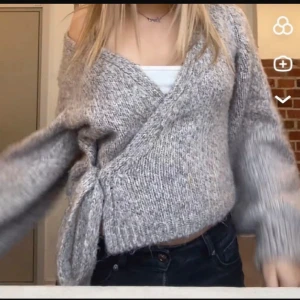 Grå stickad omlottkofta - Säljer en mysig grå stickad omlottkofta med knytband i sidan. Koftan har långa ärmar och en avslappnad passform, perfekt för kyligare dagar. Den är både stilren och bekväm, ett måste i garderoben! 💫