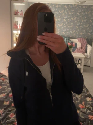 Marinblå zip hoodie från Ralph Lauren - Säljer en marinblå hoodie från Ralph Lauren med dragkedja framtill och klassisk vit logga på bröstet. Tröjan har huva och långa ärmar. Passar dig som gillar stilrena plagg.💕