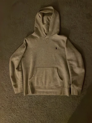 Grå Ralph lauren hoodie - Det är en grå Ralph lauren hoodie i storlek 14-16. Den sitter jätte bra i armar axlar. Passar till allt. Nypris är 1300