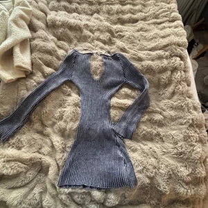 Blå ribbad stickad klänning Jaded London - Säljer en blå ribbad stickad klänning från Jaded London i storlek M. Klänningen har lång ärm, v-ringning och en snygg cut-out detalj vid bröstet. Materialet är stretchigt och figurnära, perfekt för dig som gillar trendiga och unika plagg.