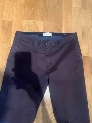 Mörkblå chinos från Scotch & Soda - Säljer ett par mörkblå chinos från Scotch & Soda i storlek W30/L34. Byxorna har raka ben, sidofickor fram och två bakfickor med knapp. Tillverkade i mjuk bomull för skön känsla och stilren look. Perfekta till både skjorta och t-shirt.