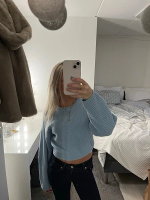 Ljusblå croppad stickad tröja - Säljer en ljusblå croppad stickad tröja med rund hals och långa ärmar. Tröjan har en relaxed fit och är perfekt för dig som gillar en enkel men snygg stil. Passar till både jeans och kjol.