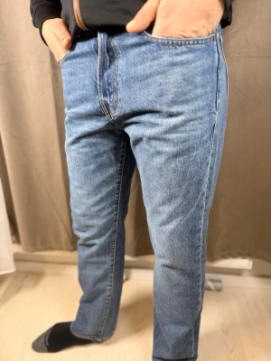 Blå raka jeans från GAP, 29/30 - Klassiska blå jeans från GAP i rak modell med normal passform. Jeansen har fem fickor, gylf med dragkedja och är tillverkade i slitstarkt denimtyg av bomull. Perfekta för en avslappnad och tidlös look.