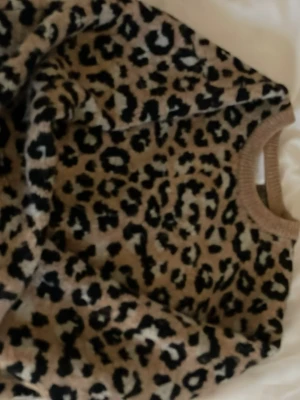 Leopardmönstrad beige tröja - Säljer en supermjuk och cozy tröja med leopardmönster i beige och svart. Rund halsringning med ribbad kant och långa ärmar. Perfekt för dig som vill sticka ut lite extra och älskar djurmönster!