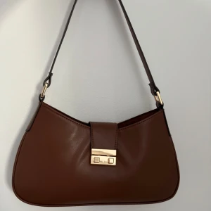 Väska - En brun fin väska, knappt använd. Passande till vardagliga livet. Får plats med mobilen, nycklar, plånbok och mycket mer.