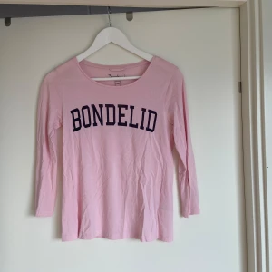 Bondelid topp  - Långärmad fin topp från bondelid i ljusrosa nyans. Perfekt topp för sommarens kvällar med en långärmad tröja.  Säljer den pga att mina axlar blivit bredare och tröjan för liten. Stl xs Tipps - styla med en vit kofta till. 