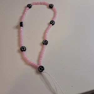 Pärlor mobil accessoarer - Ett handgjort pärl mobil acesoar med små rosa pärlor och större svarta pärlor med vita detaljer. perfect för mänga mobil skal. 