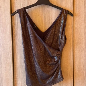 Crossover linne med gulddetaljer - Brunt linne med gulddetaljer och tjocka axelband. Crossover vid bröstet✨ nyskick
