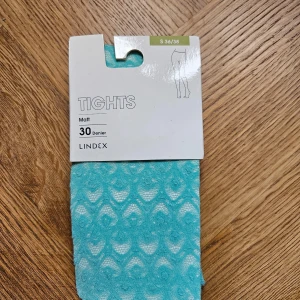 Matt turkosa strumpbyxor från Lindex - Turkosa strumpbyxor från Lindex med mönster. Strumpbyxorna har en tjocklek på 30 denier och är tillverkade av 86% polyamid och 14% elastan.
